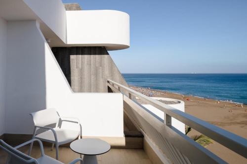 a balcony with two chairs and a view of the beach at Plus Fariones Suite Hotel in Puerto del Carmen