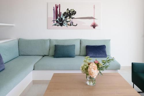 a living room with a couch and a table with flowers at Plus Fariones Suite Hotel in Puerto del Carmen
