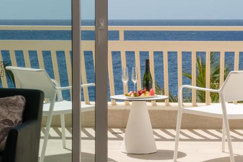 a table with a plate of fruit and wine glasses on a balcony at Plus Fariones Suite Hotel in Puerto del Carmen