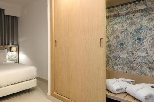 a room with a bed and a cabinet with towels at Plus Fariones Suite Hotel in Puerto del Carmen
