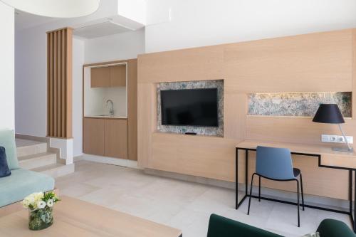 a living room with a table and a tv on a wall at Plus Fariones Suite Hotel in Puerto del Carmen