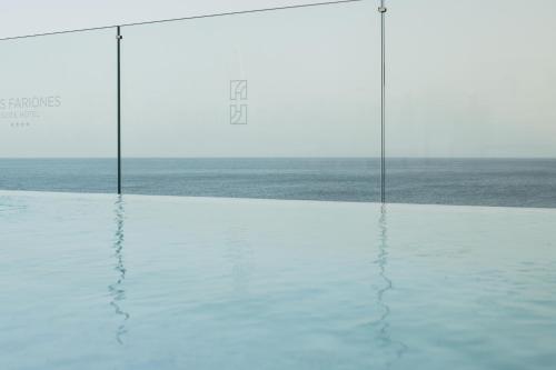 a pool of water with a view of the ocean at Plus Fariones Suite Hotel in Puerto del Carmen