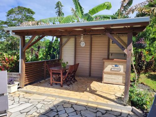 a wooden pergola with a table and a wooden table at Fleur de canne in Sainte-Rose