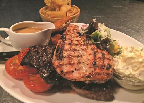 a plate of food with meat and vegetables and sauce at The Kellbank in Gosforth