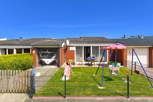 um quintal com um baloiço no quintal em Strandnahes Ferienhaus Mit Kinderspielplatz em Esens