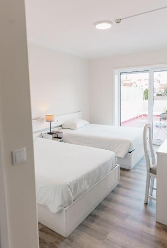 two beds in a room with a table and a chair at Arca Nova Guest House - Caminha in Caminha