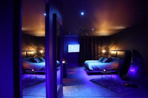 - une chambre avec 2 lits dans une chambre avec des lumières violettes dans l'établissement Suite Chic&Sensuelle La Manova SPA&Loveroom, à Saint-Martin-dʼAuxigny