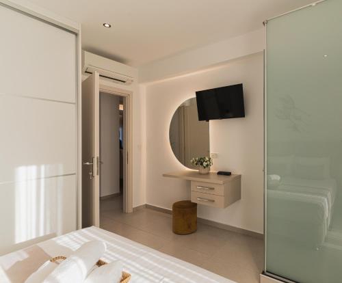 a bedroom with a glass shower and a tv on the wall at G-Ammos 5 Star Villa by elite in Tragaki