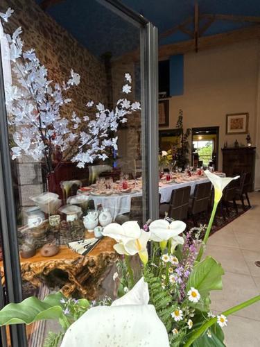 une chambre avec une table et des fleurs devant elle dans l'établissement Les Philous Gourmands, à LʼÉpaux