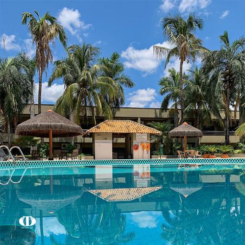 a swimming pool with chairs and umbrellas and palm trees at Hotel OT in Três Lagoas