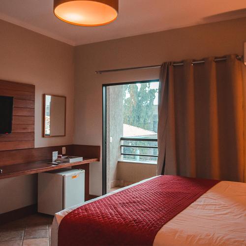 a bedroom with a bed and a window and a desk at Hotel OT in Três Lagoas