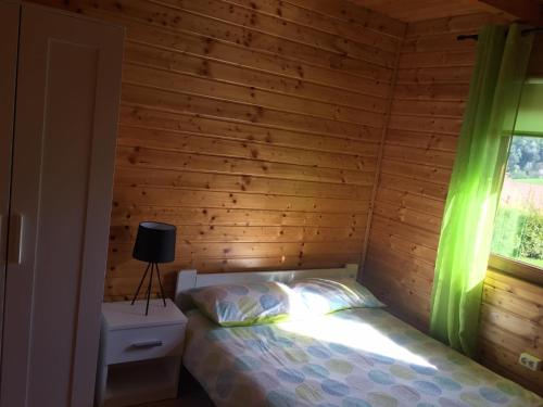 a bedroom with a bed and a window with green curtains at Solina - Jezioro Solińskie - Domki in Wołkowyja