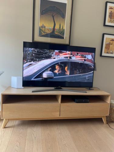 TV de pantalla plana en la parte superior de un centro de entretenimiento de madera en City Center (2bedroom/1bath/Balcony) Sørenga, en Oslo