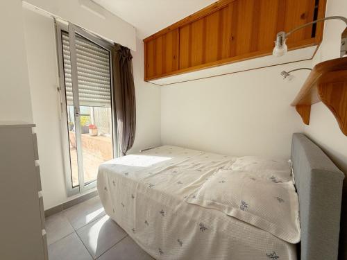 un petit lit dans une chambre avec une fenêtre dans l'établissement L'Olivier, à Sainte-Maxime