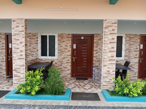 a brick house with two benches and a door at Sathyam Resorts in Dharmapuri