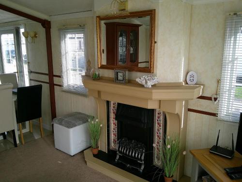 ein Wohnzimmer mit Kamin und Spiegel in der Unterkunft The Wolds Vogue II 6 Berth Central Heated in Ingoldmells