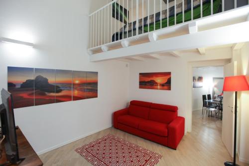 a living room with a red couch and a staircase at Carlo Alberto 46 in Pavia