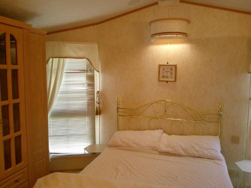ein Schlafzimmer mit einem weißen Bett mit einem Fenster in der Unterkunft The Wolds Vogue II 6 Berth Central Heated in Ingoldmells