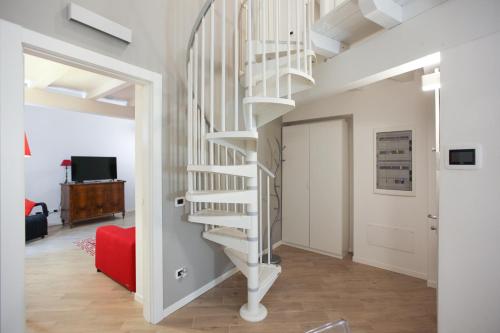 a spiral staircase in a living room with a red couch at Carlo Alberto 46 in Pavia