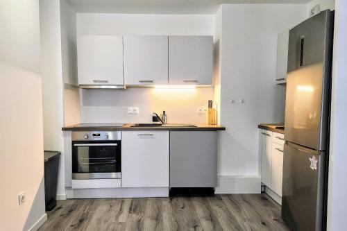 une cuisine avec des armoires blanches, un évier et un réfrigérateur dans l'établissement Modern 2BR balcony secured parking metro 14, à Saint-Ouen