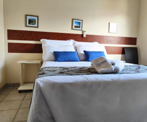 a bedroom with a large bed with blue pillows at Hotel Minastur in Capitólio