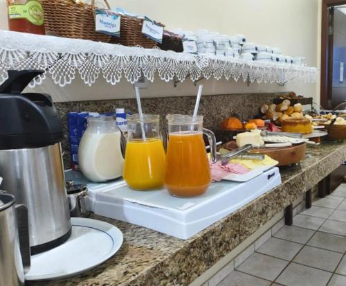 a counter with three glasses of orange juice at Hotel Minastur in Capitólio
