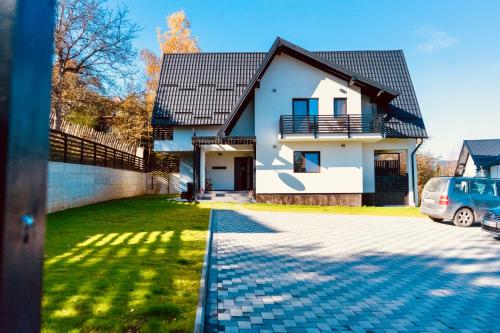a house with a car parked in the driveway at Pensiunea CityView in Câmpulung Moldovenesc