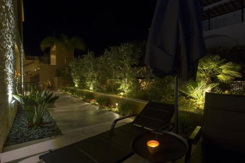 a patio with a chair and an umbrella and lights at Almi-Cove Hilltop Villas in Almirida