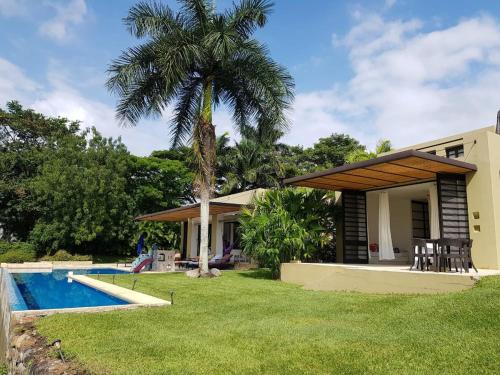 a house with a palm tree and a swimming pool at Villa en Club Campestre Mesa de Yeguas in Anapoima