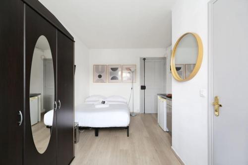 une chambre blanche avec un lit et un miroir dans l'établissement Studio moderne hopital Cochin - Paris 13 - 2P, à Paris