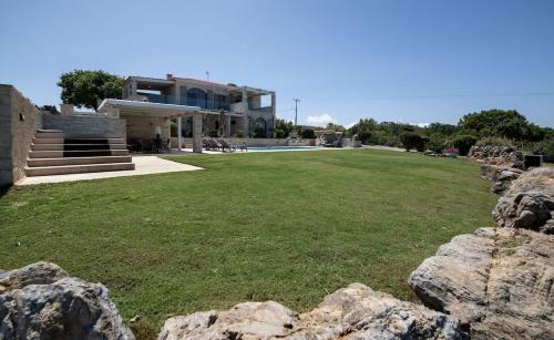 a large yard with rocks in front of a house at Villa AuroraLuxurius Living in Prinés
