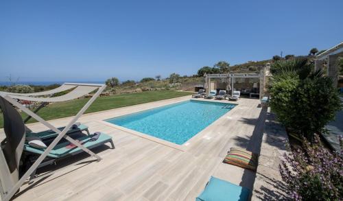 a pool with chairs and a hammock next to a house at Villa AuroraLuxurius Living in Prinés