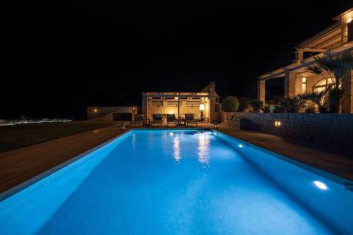 a large blue swimming pool in front of a house at night at Villa AuroraLuxurius Living in Prinés
