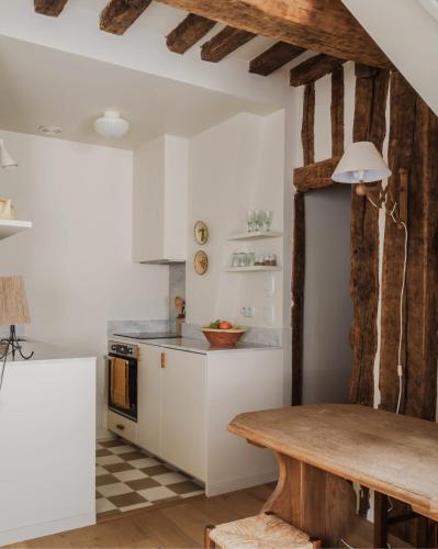 une cuisine avec des armoires blanches et une table en bois dans l'établissement Appartement de charme dans le centre de Rouen, à Rouen