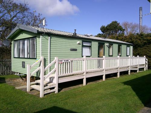a green tiny house with a white fence at Seaview Burgundy 8 Berth Central heated in Ingoldmells