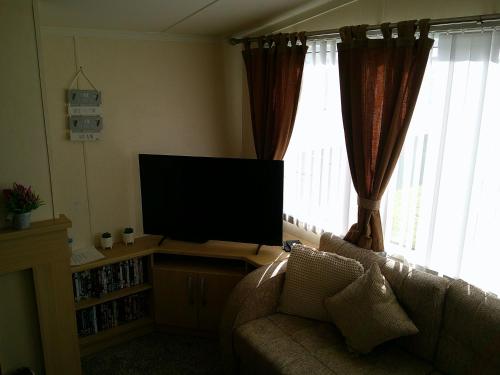 a living room with a couch and a flat screen tv at Seaview Burgundy 8 Berth Central heated in Ingoldmells