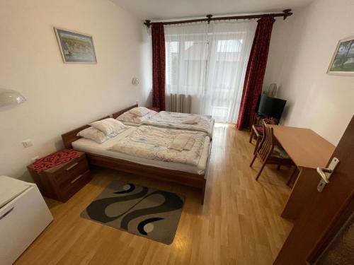 a small bedroom with a bed and a desk at Koller Panzió in Bonyhád