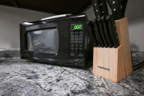 a microwave sitting on a counter next to a block of knives at The Cozy and Quaint Duplex in Point in Stevens Point