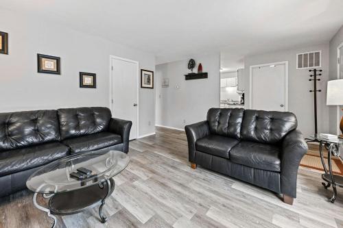 a living room with a leather couch and a table at The Cozy and Quaint Duplex in Point in Stevens Point