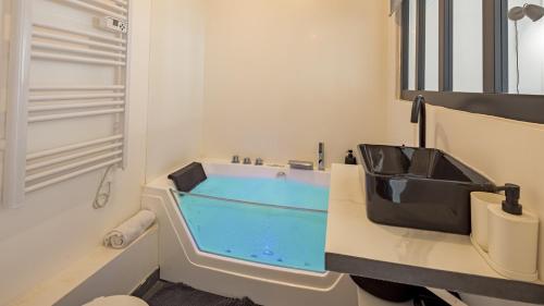 La salle de bains est pourvue d'un lavabo noir et d'une baignoire bleue. dans l'établissement Le Reflet Secret - Hypercentre - Balnéo, à Troyes