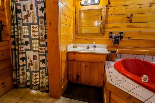 a bathroom with a red sink and a red tub at Cozy Cabin Wgame Room, Hot Tub & Creek in Pigeon Forge