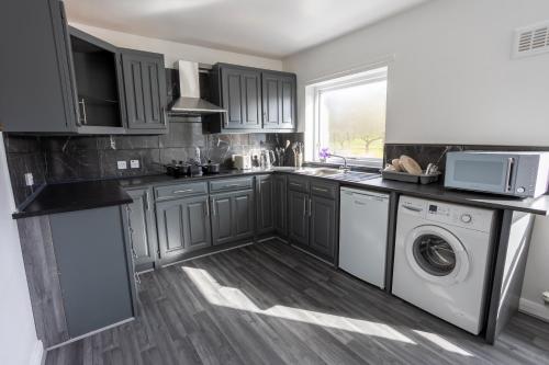 a kitchen with gray cabinets and a washer and dryer at Charming 2br Maisonette In Carlisle Center in Carlisle