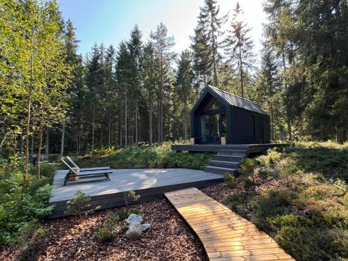a black cabin in the woods with a wooden deck at PAUS puhkemaja in Põõsaspea