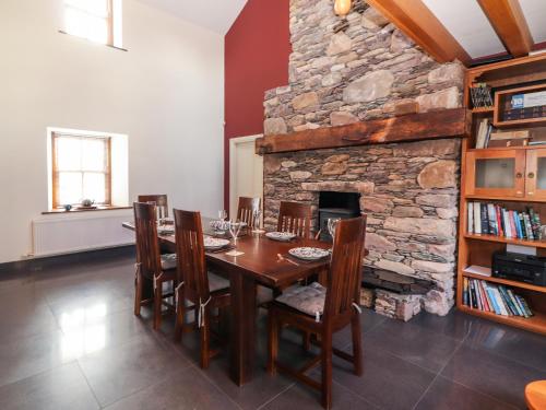 a dining room with a table and a stone fireplace at Johnson's Cottage in Brandon