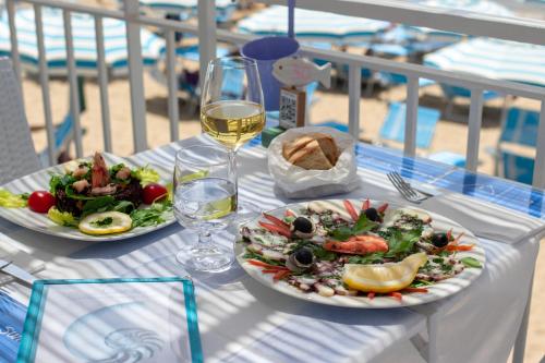a table with two plates of food and a glass of wine at Hotel Aurora in Sperlonga