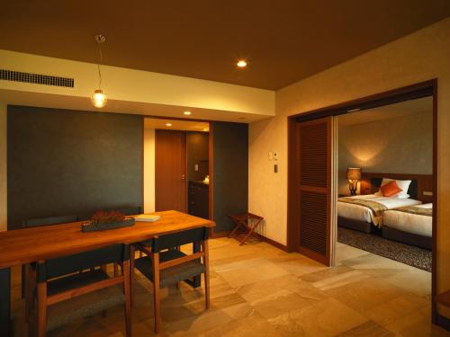 a room with a dining table and a bedroom at Hotel Anaga in Minamiawaji