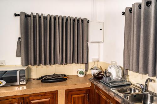 a kitchen with black curtains and a sink and a microwave at 007Dickoya in Dikoya