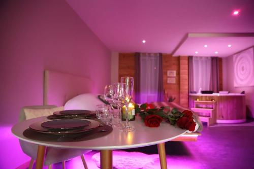Cette chambre violette comprend une table avec des verres à vin et des roses. dans l'établissement Suite Chic&Sensuelle La Manova SPA&Loveroom, à Saint-Martin-dʼAuxigny