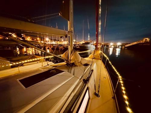 a boat in the water at night with lights at Sleep aboard a modern sailboat in Oeiras in Oeiras