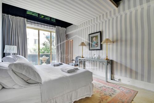 une chambre blanche avec un grand lit et une fenêtre dans l'établissement Luxurious & Calm Balcony Facing Bois de Boulogne, à Neuilly-sur-Seine